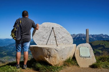 HOCHSOELL, TYROL, AUSTRIA - AUGUST 25, 2016. Sundial at the panoramic trail around Hohe Salve mountain, Wilder Kaiser at the back, Kitzbhel Alps, Tyrol, Austria clipart