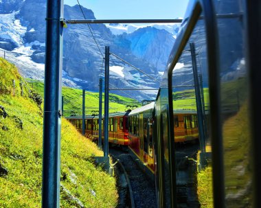 Jungfraujoch 'tan (Avrupa' nın tepesi) Kleine Scheidegg, Bernese Oberland, İsviçre 'ye kadar meşhur Jungfrau Demiryolu' nun çarkıfelek kırmızı treniyle güzel bir manzara.