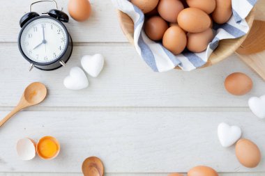 Beyaz mutfak masasında taze çiğ yumurta, sarı sarısı yumurta, beyaz kalp şekli işareti ve Klasik vintage saat ile metin için boşluk çerçeve kopyalayın. yüksek protein gıda kavramı.