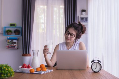 kahvaltı masası Genç Asyalı kadın ile oturma odasında biraz süt iç. gülen yüz.
