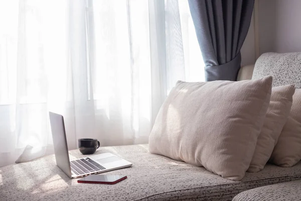 white bed with blank screen on laptop and alarm clock in bedroom
