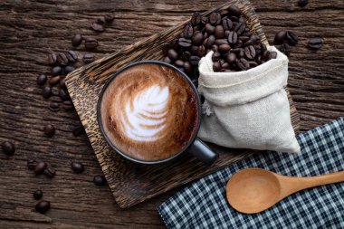 ahşap masada kahve taneleri ile latte kahve fincan.