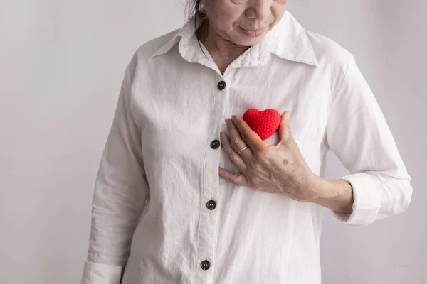 Smiling asian elderly woman holding red heart shape, concept of — Stock Photo, Image