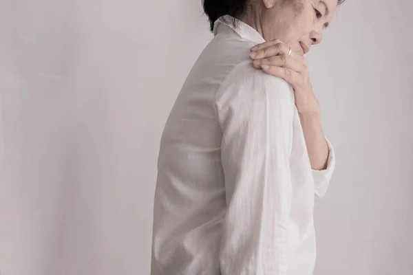 Asian elderly woman having shoulder pain on isolated white backg — Stock Photo, Image