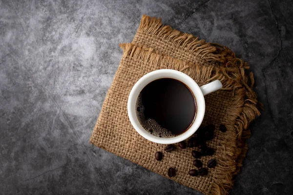 Taza de café negro y granos de café sobre fondo de textura de cemento , — Foto de Stock