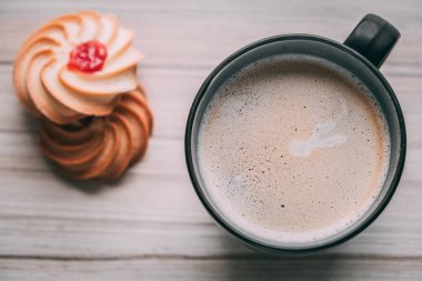 Süslü, köpüklü bir kahve fotografı, siyah bir kupayla, şekerli ve kurabiyeli, ahşap arka planda, doğal ışıklandırma..