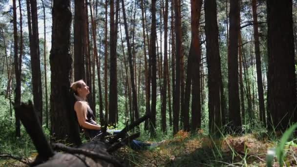 Flicka Skog Sitter Lutad Mot Ett Träd Med Hörlurar Lyssnar — Stockvideo