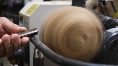 Önlüklü bir adam ahşap torna tezgahında çalışıyor. Eller keskiyi tutar. Hobi. Kapat. evde çalışmak