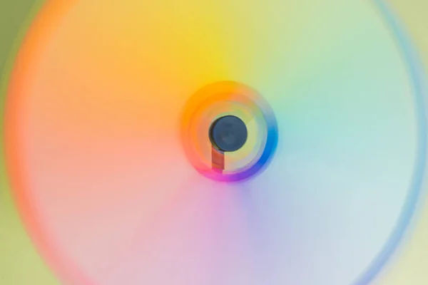 Yeşil arka planda çok renkli bir rüzgar oyuncağı. Bıçaklar gökkuşağı şeklinde bulanık bir iz bırakıyor. LGBTQ + işareti, amblem. Metin için boşluk