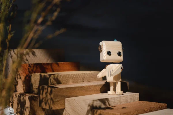 Tahta bloklardan yapılmış küçük tahta robot merdivenleri çıkıyor. konsepti yükselt