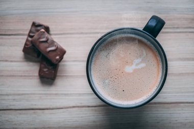Süslü, köpüklü bir kahve fotografı, siyah bir kupayla, şekerli ve kurabiyeli, ahşap arka planda, doğal ışıklandırma..