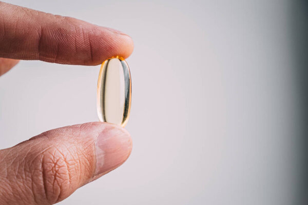 yellow transparent omega 3 capsules in hand. taking medications. nutritional supplements