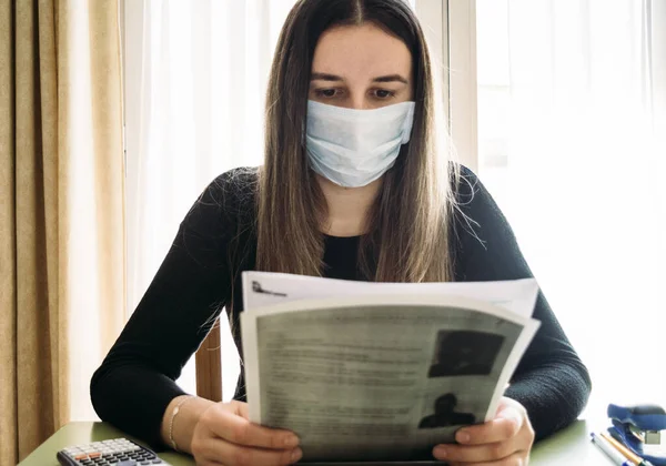 Girl with a surgical mask and studying at home during quarantine. Classes online. Locked up at home. Quarantine. Covid-19 pandemic coronavirus.