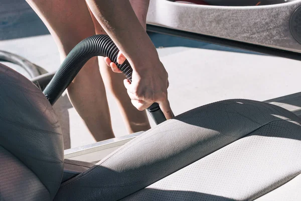 A woman's hand cleaning a car with a vacuum cleaner.