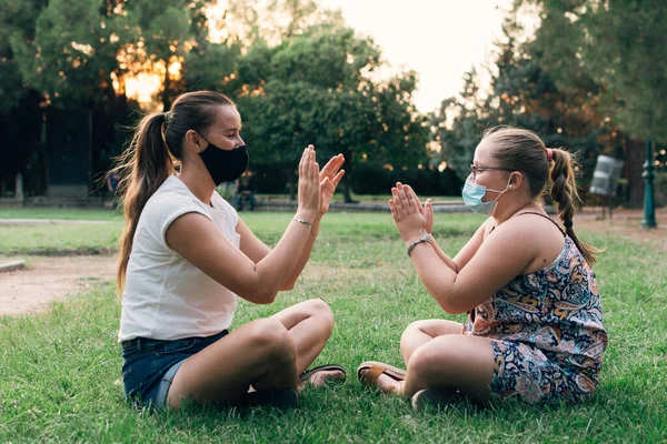 Mother and daughter with face masks playing in the park.