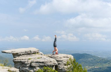 Çocuk dağ taşında yoga pozu veriyor.