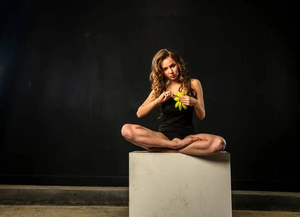girl in black in lotus position meditates with lotus in hand