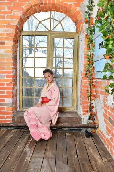Çiçeklerin Arka Planında Pembe Japon Kimonolu Kız Pencerede Rüyalar Görüyor — Stok fotoğraf