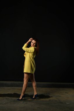 Siyah arka planda poz veren sarı elbiseli güzel bir kız.