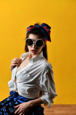 Beyaz bluzlu güzel bir kız. Sarı arka planda poster tarzı poz veriyor.