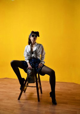 Beyaz bluzlu güzel bir kız. Sarı arka planda poster tarzı poz veriyor.