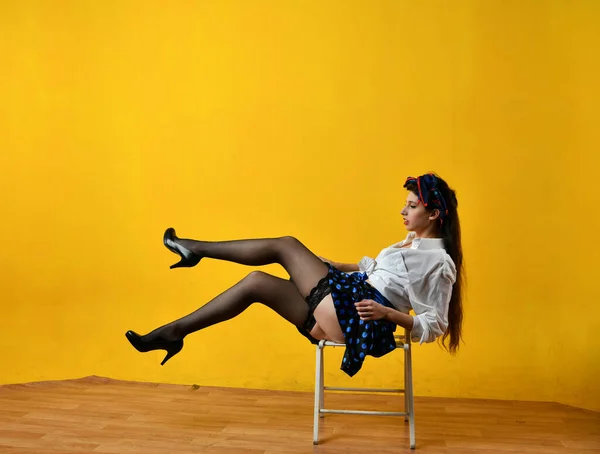 beautiful girl in a white blouse posing in pin-up style on a yellow background