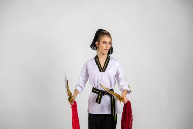 Beyazlar içindeki güzel kız dövüş kılıçlarıyla kung fu eğitimi alıyor.