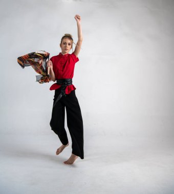 Siyah ve kırmızı elbiseli güzel kız savaş eşarbıyla dans ediyor.