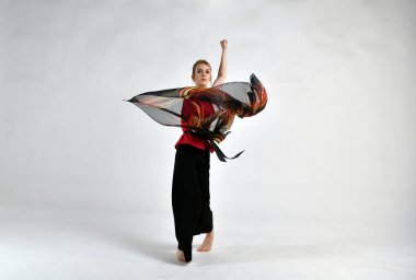 Siyah ve kırmızı elbiseli güzel kız savaş eşarbıyla dans ediyor.