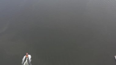 Motorlu tekneler nehir boyunca bir insansız hava aracından çekilen güzel bir manzaranın arka planına karşı gider.