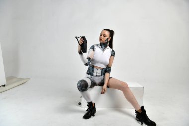 Robot kostümlü bir kız eski teknoloji dışı eşyalarla poz veriyor.