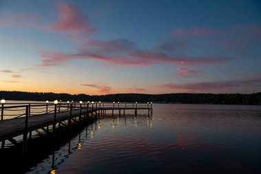Gün doğumunda nehirde pembe bulutların yansıması