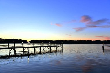 Gün doğumunda nehirde pembe bulutların yansıması