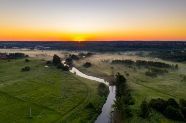 Şafak vakti insansız hava aracından çekilen yeşil tepedeki beyaz taş manastırın panoramik görüntüsü