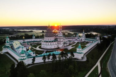 panoramic view of a white stone monastery on a green hill filmed from a drone at dawn clipart