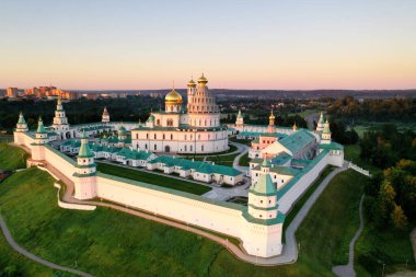 Şafak vakti insansız hava aracından çekilen yeşil tepedeki beyaz taş manastırın panoramik görüntüsü