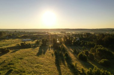 Şafakta insansız hava aracından alınan bir nehirle sisli yeşil alanların panoramik görüntüsü