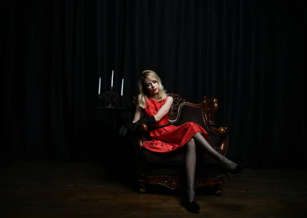 Kırmızı Elbiseli Güzel Bir Kız Siyah Arka Planda Bir Sandalyede — Stok fotoğraf