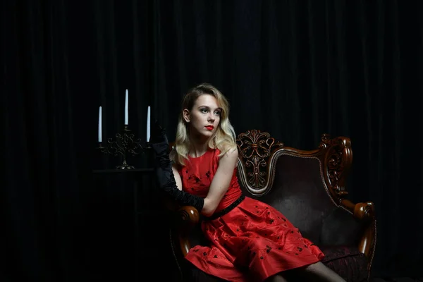 Kırmızı Elbiseli Güzel Bir Kız Siyah Arka Planda Bir Sandalyede — Stok fotoğraf