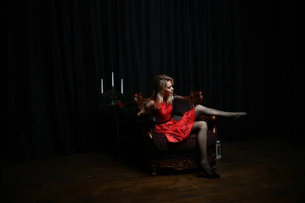 Gyönyörű Lány Piros Ruhában Pózol Fotelekben Vár Egy Fekete Háttér — Stock Fotó