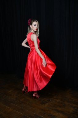 Siyah arka planda poz veren kırmızı elbiseli güzel kız.