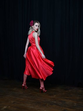 Siyah arka planda poz veren kırmızı elbiseli güzel kız.