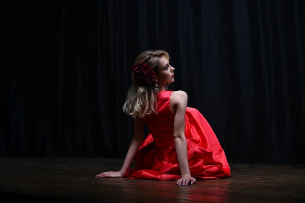 白いバラを背景にした美しい夜の赤いドレスを着た女の子 — ストック写真
