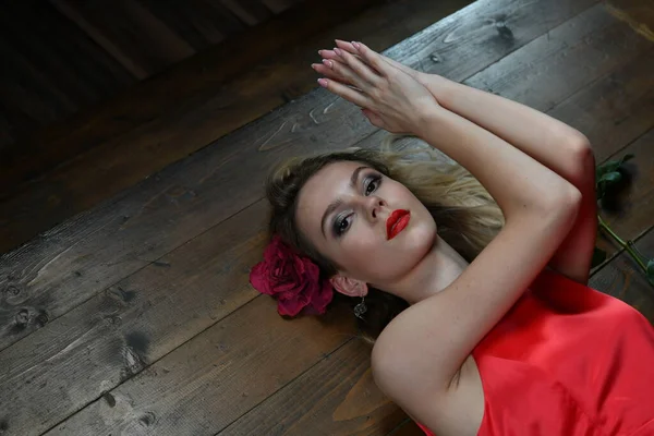 美しい赤のドレスを着た少女が黒い背景に床に横たわっています — ストック写真