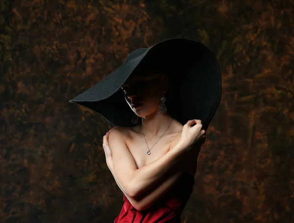 黒い帽子の美しい少女とバーガンディのイブニングドレスが腕に包まれ — ストック写真