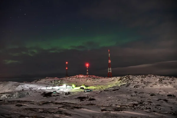 green flashes of the northern lights at night in the arctic are observed from the top of the hill