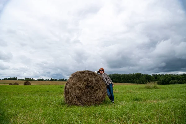 Kobieta Spoczywa Pobliżu Stogu Siana Naturze Przeciwko Szaremu Niebu — Zdjęcie stockowe