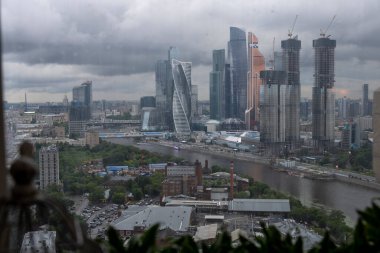 Pencereden yağmur yağdığını görebileceğiniz büyük bir şehir manzarası.