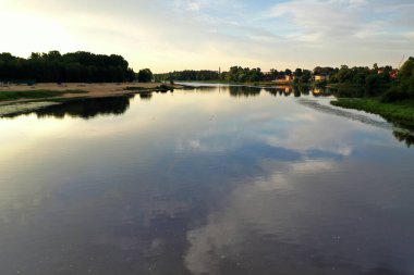 Şafak vakti yansıtan ağaçlar ve bulutlarla dolu nehir bir drondan filme alınmıştır.