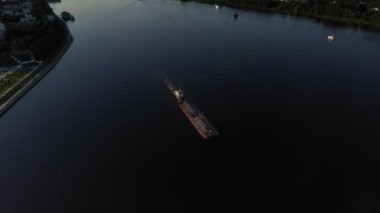 Üzerinde bir mavna yüzen büyük mavi bir nehrin panoramik görüntüsü İHA 'dan çekilmiş.